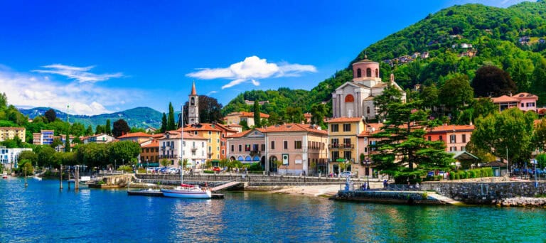 Lakeside town with colorful buildings, lush green hills, and a serene waterfront view, perfect for t.