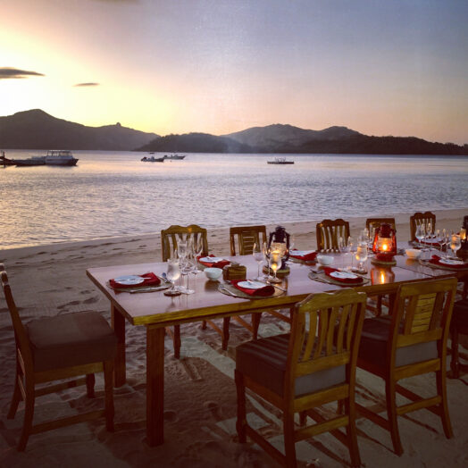 A dining table at sunset on the beach in Fiji