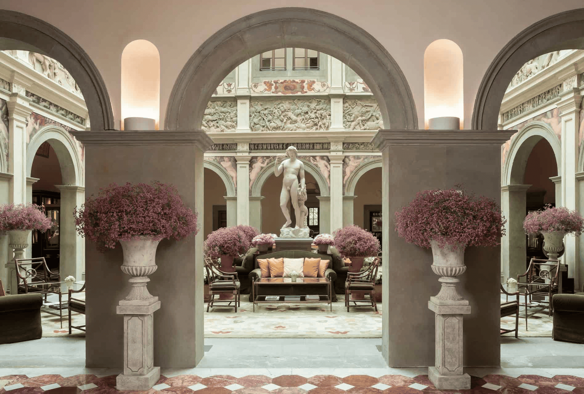 Luxurious hotel lobby featuring classical architecture, marble columns, and floral arrangements.