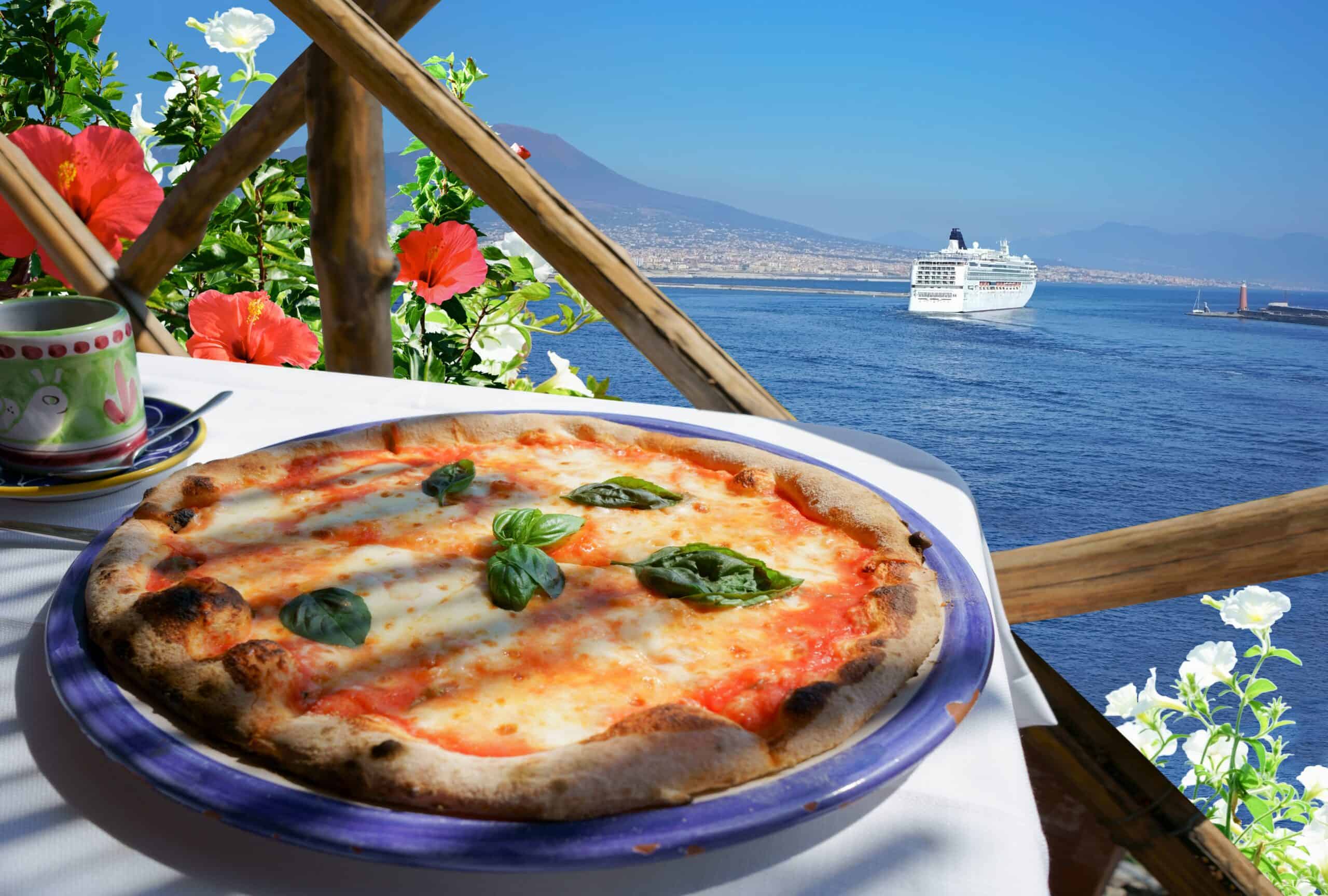 Delicious Margherita pizza on a seaside terrace overlooking the ocean and a cruise ship in the dista.