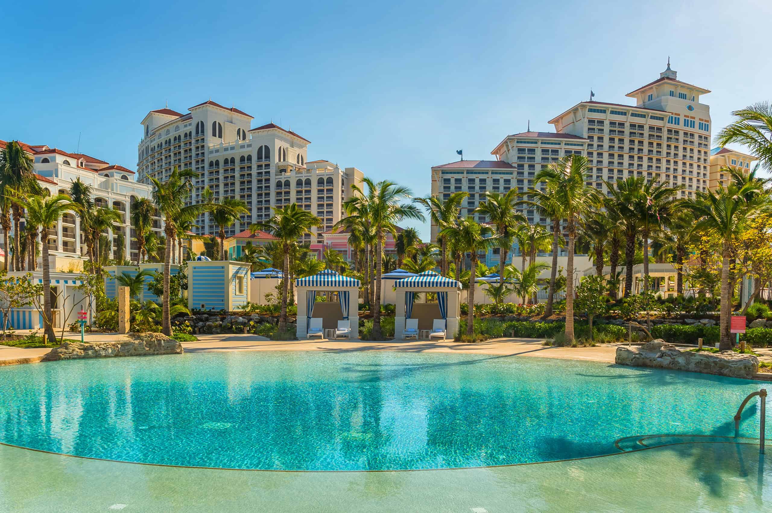 Luxurious Caribbean resort pool with palm trees and high-rise buildings.