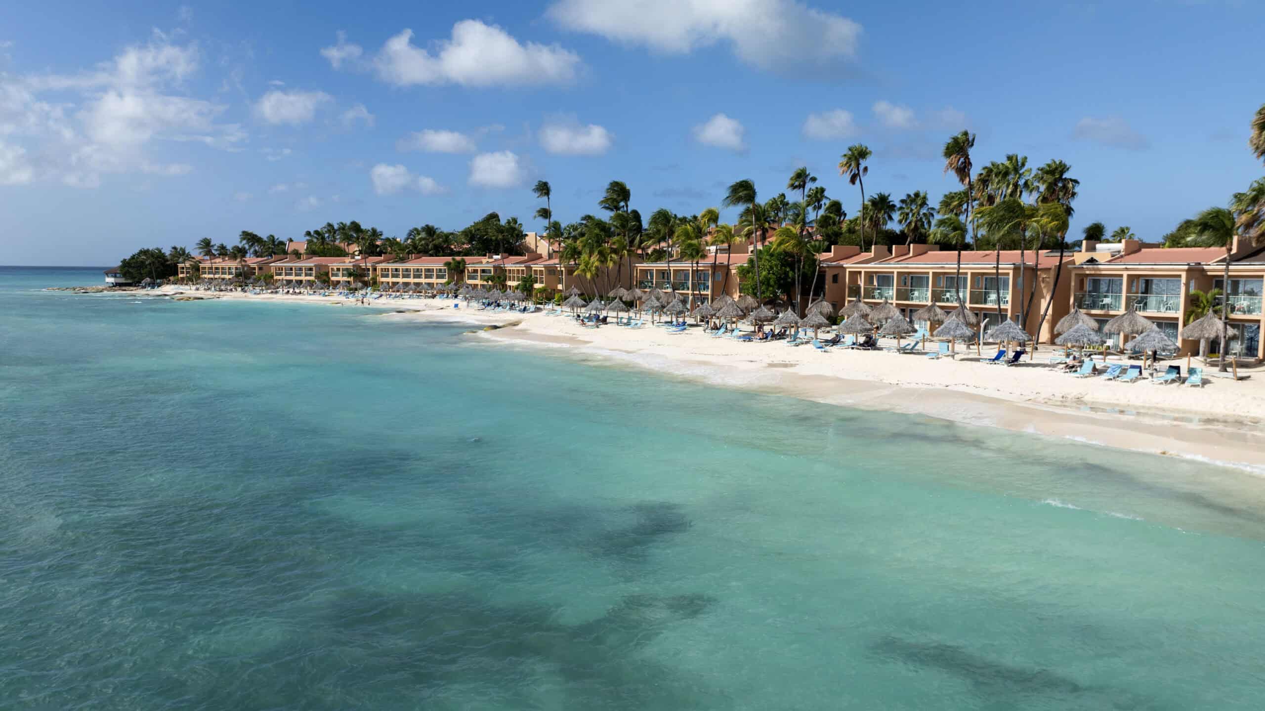Beachfront Caribbean resort with clear waters, palm trees, and luxurious accommodations.