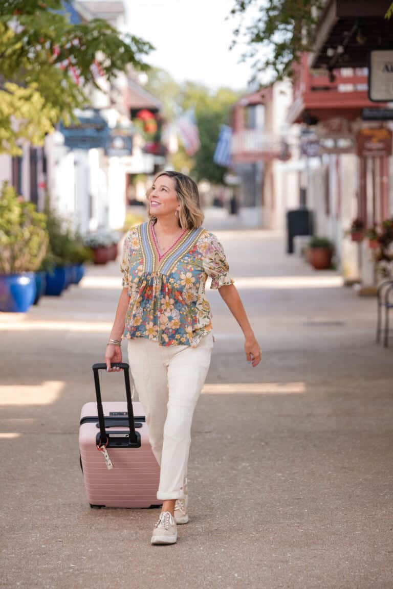 Travel woman with suitcase walking on a scenic street, enjoying her travel adventure.