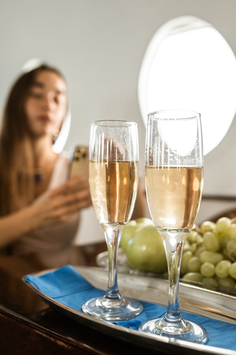 Elegant champagne glasses on a tray with blurred background of woman in a private jet.