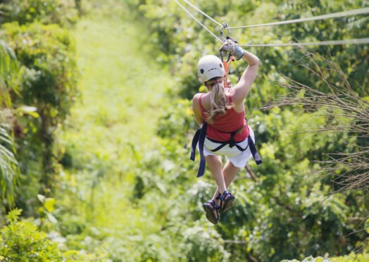 Woman enjoying a fun zip line tour in the jungle of Kauai