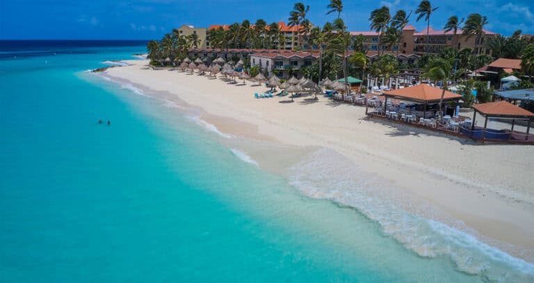 Beautiful tropical beach with turquoise waters and resort accommodations in the background.