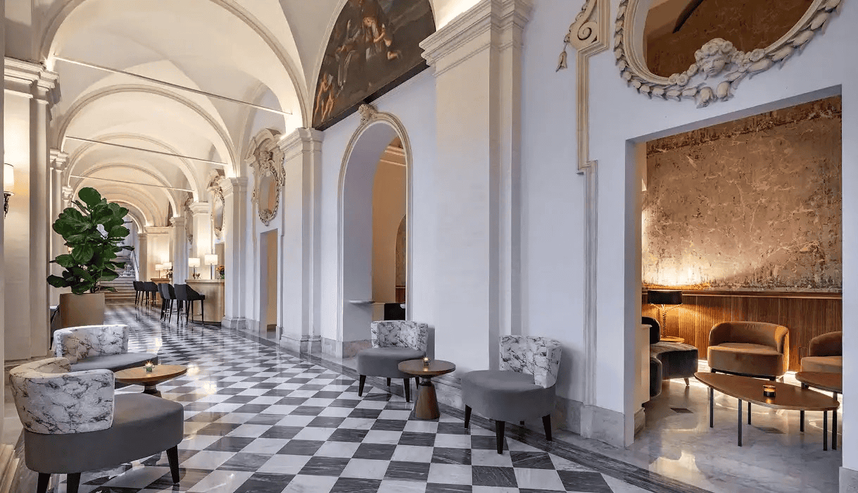 Elegant hotel lobby with arches, checkered floor, and stylish seating areas for travelers.