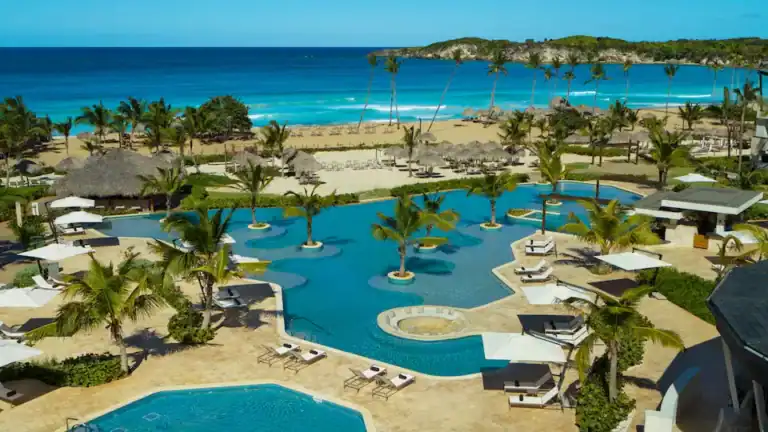 Pool area at Punta Cana resort with palm trees and ocean backdrop.