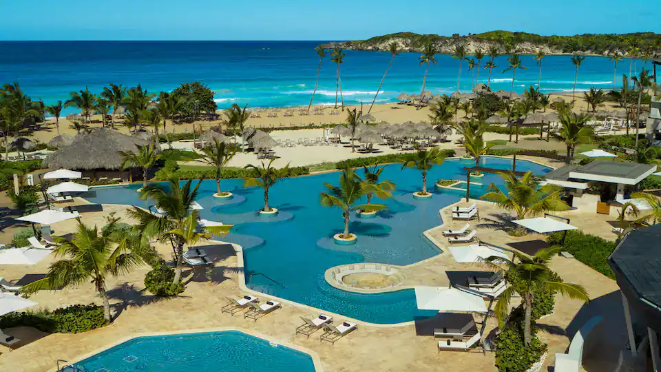 Pool area at Punta Cana resort with palm trees and ocean backdrop.