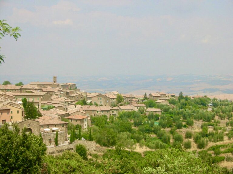 Scenic hillside village with lush greenery, terraced houses, and rolling landscape in the background.
