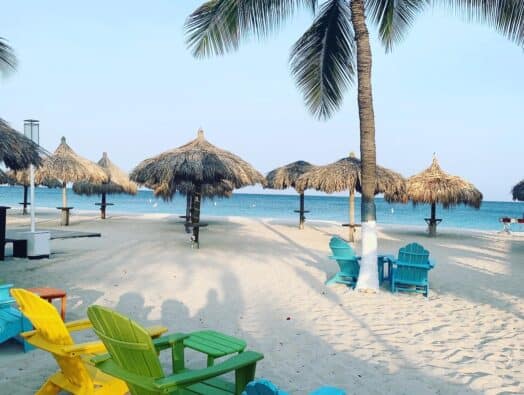 Relaxing Florida beach with palm trees, colorful chairs, and thatched umbrellas on soft sand. Perfec.