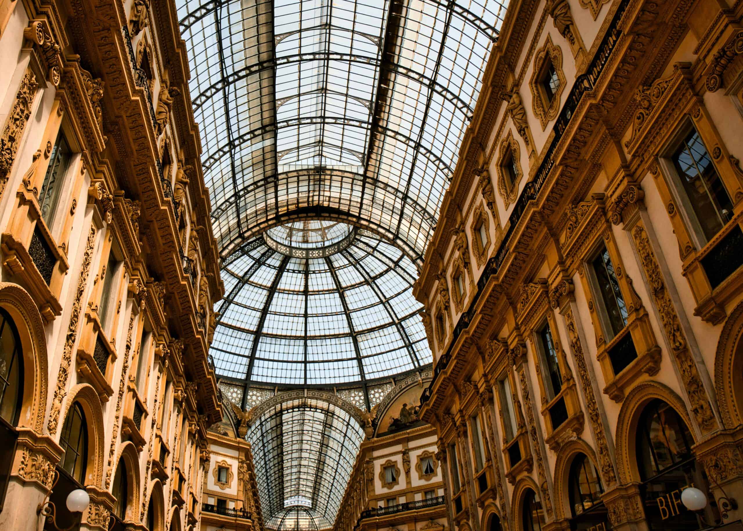Milan shopping gallery with glass ceiling, ornate architecture, and luxurious interior design.
