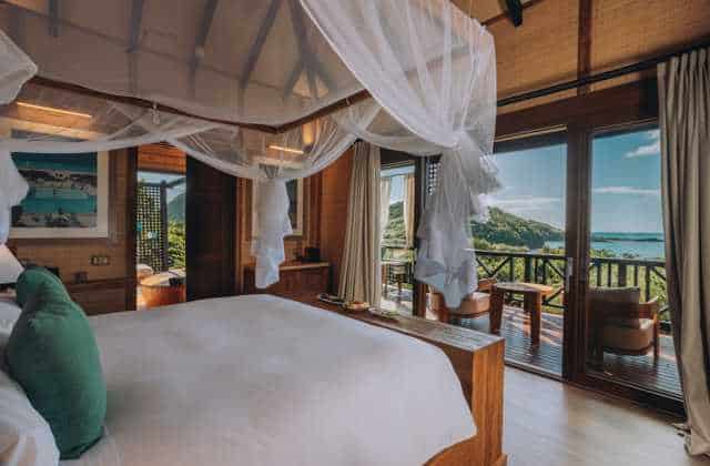 Luxury beachfront bedroom with ocean view and balcony, tropical decor, and natural light. Perfect fo.