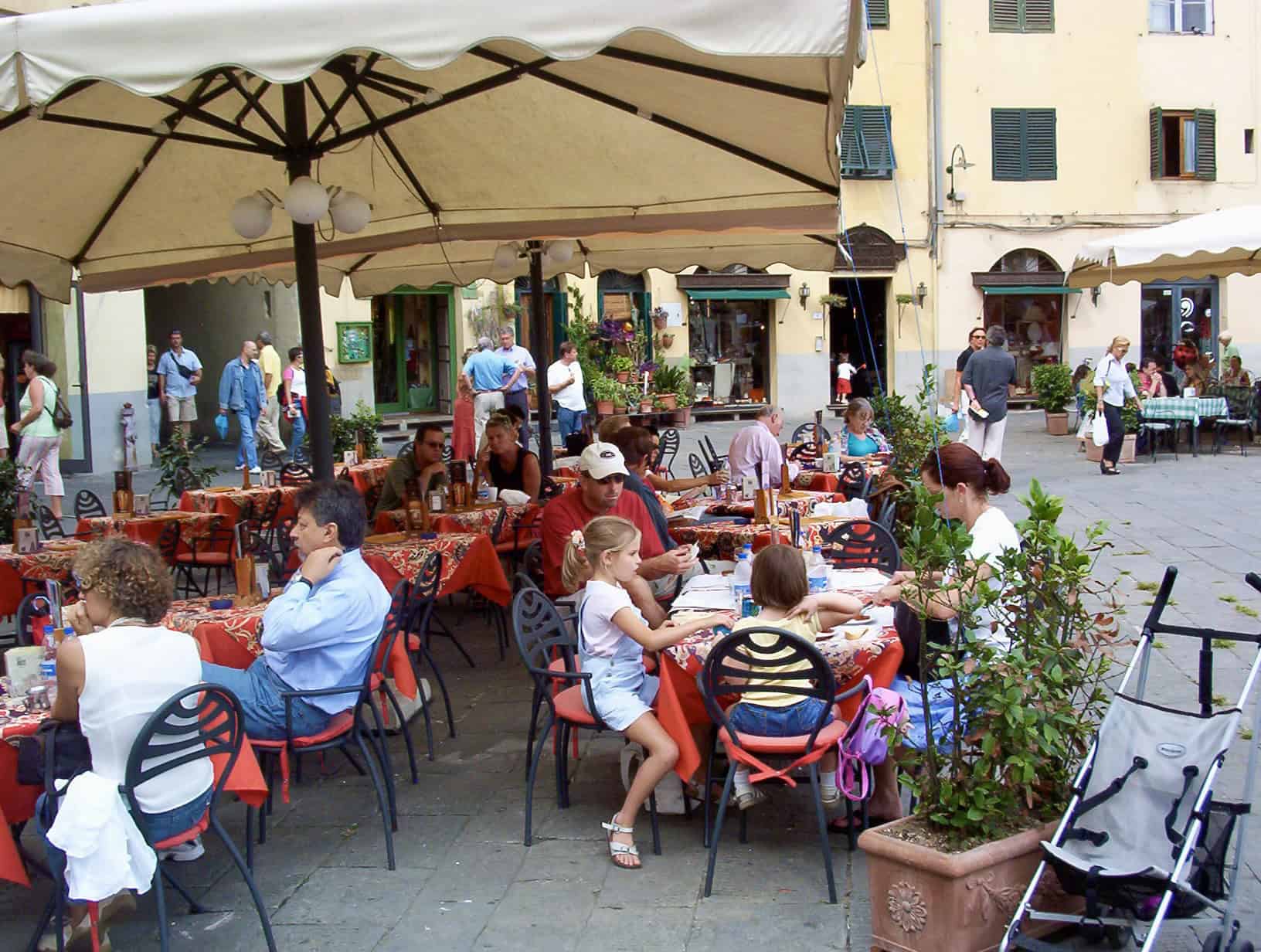 Al fresco dining scene in a charming European town square with families and friends enjoying meals o.