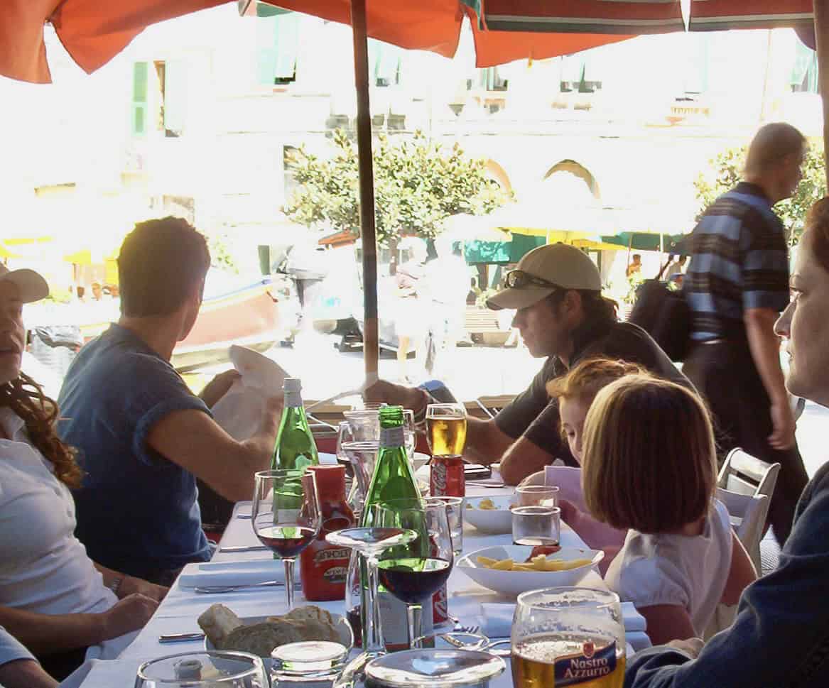 Outdoor restaurant scene with people enjoying drinks and conversation.