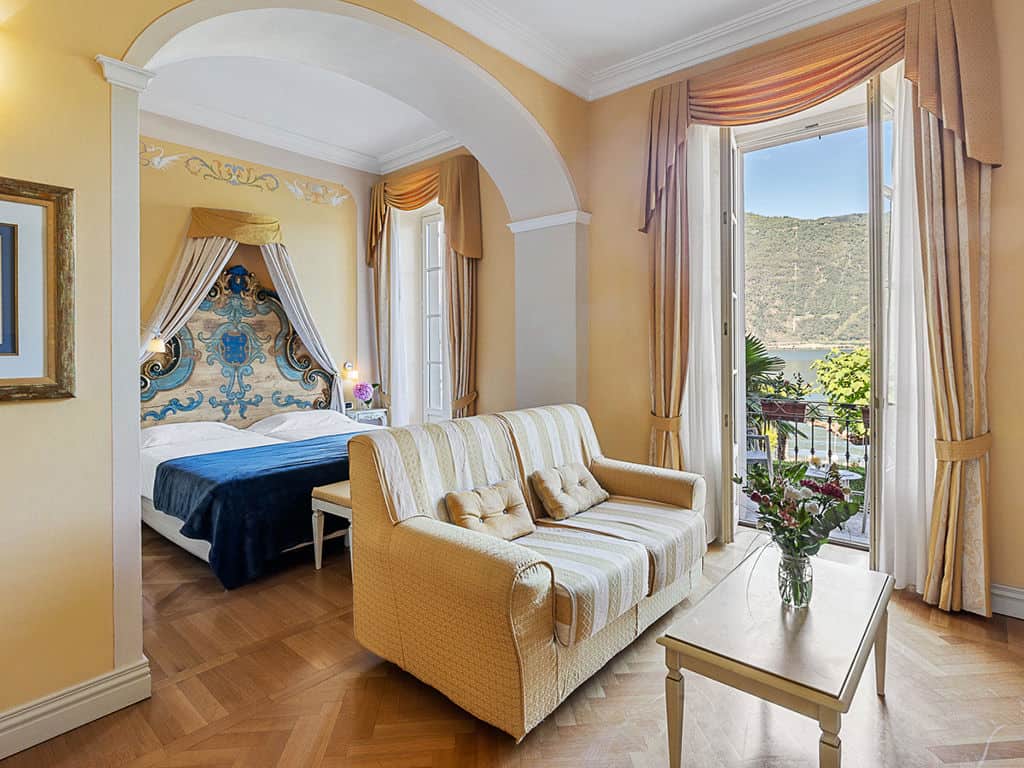 Hotel room overlooking Lake Maggiore with elegant decor and a balcony.