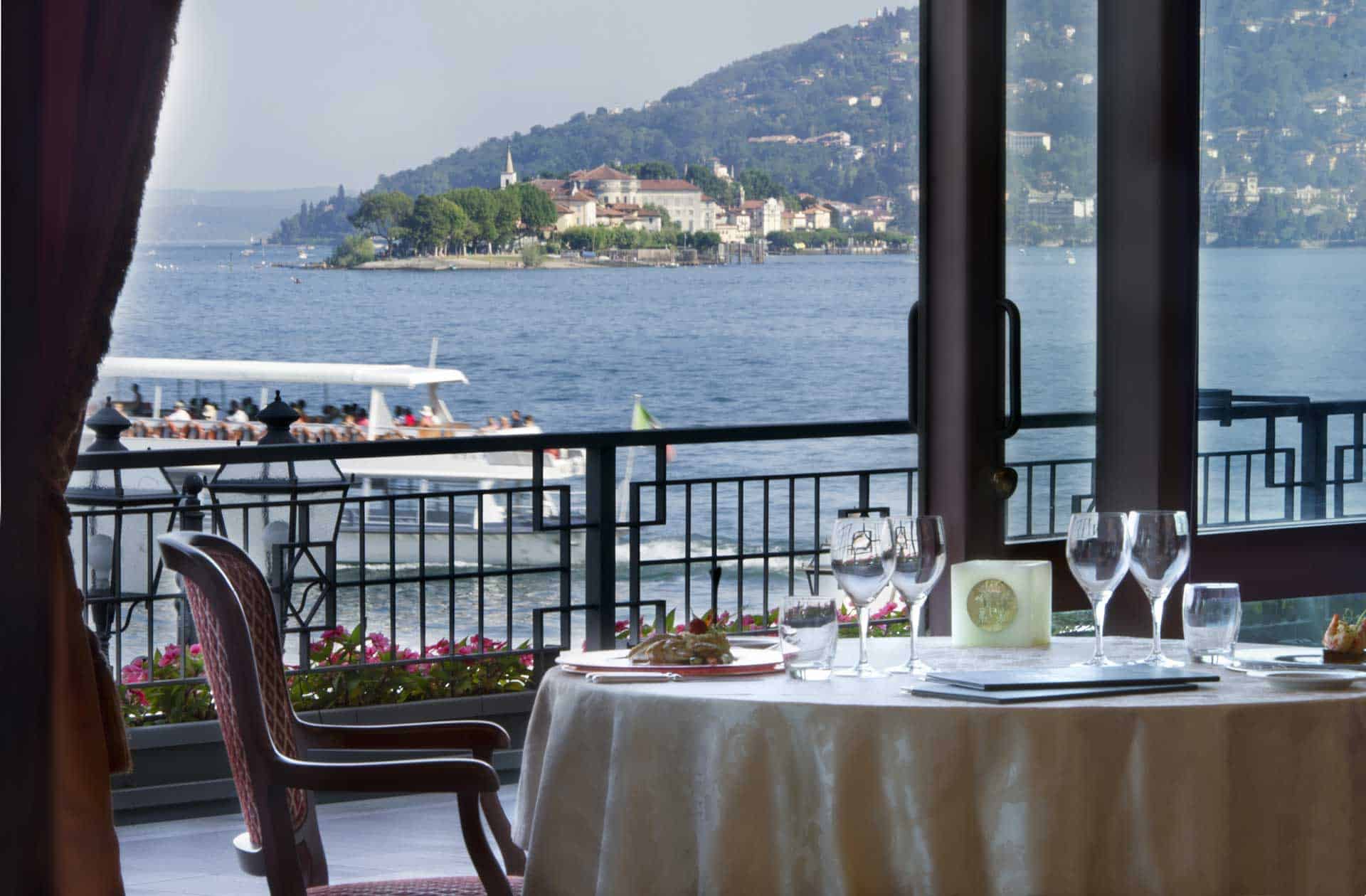 Scenic lakeside restaurant on Lake Maggiore with elegant table setting and beautiful water views. Pe.