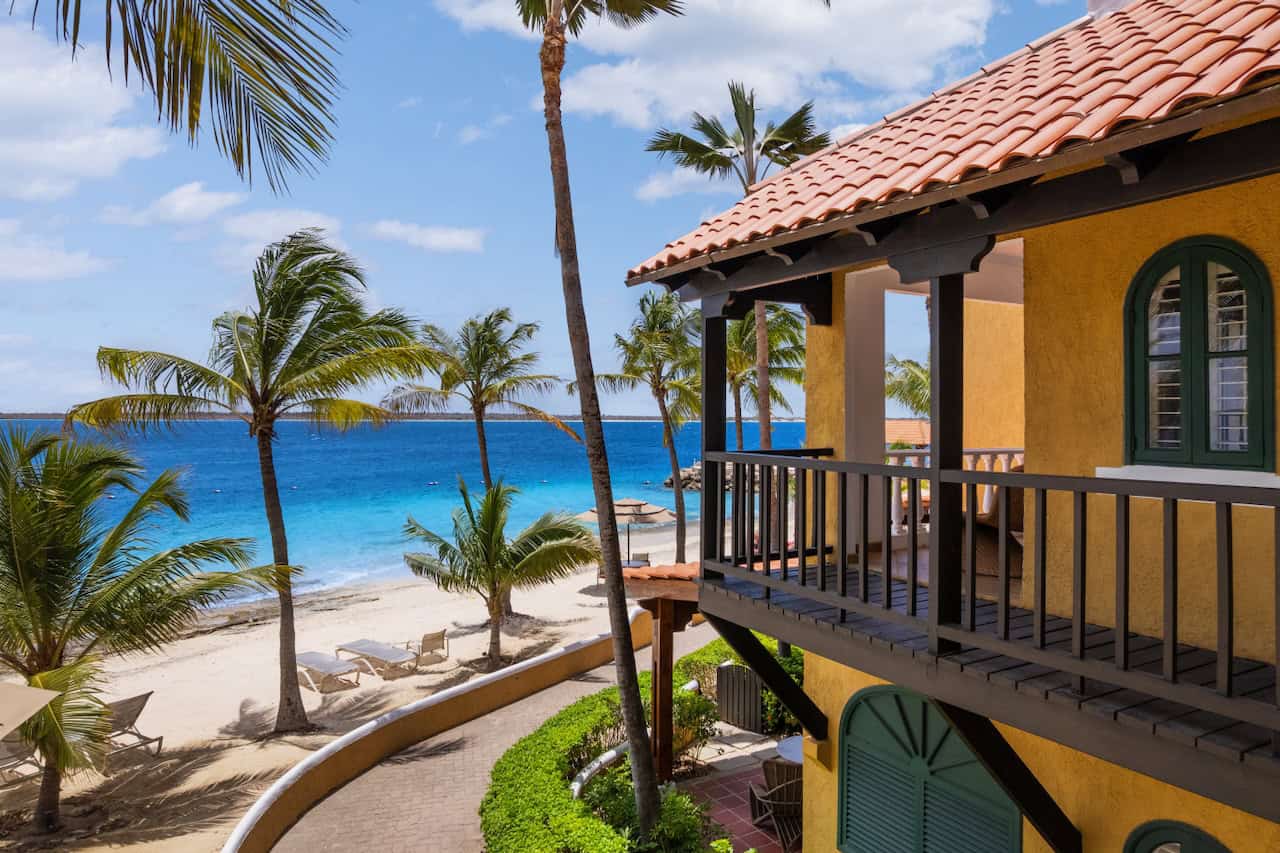 Beachside Caribbean villa with palm trees, turquoise ocean, and sandy beach view.