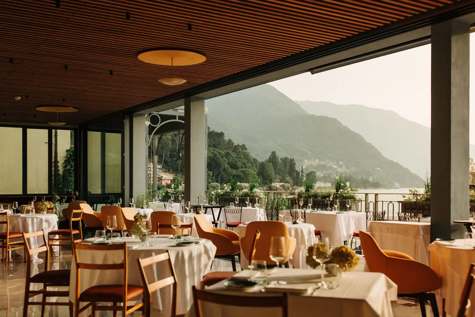 Lakeside restaurant on Lake Como with mountain scenery, outdoor seating, and elegant table settings.