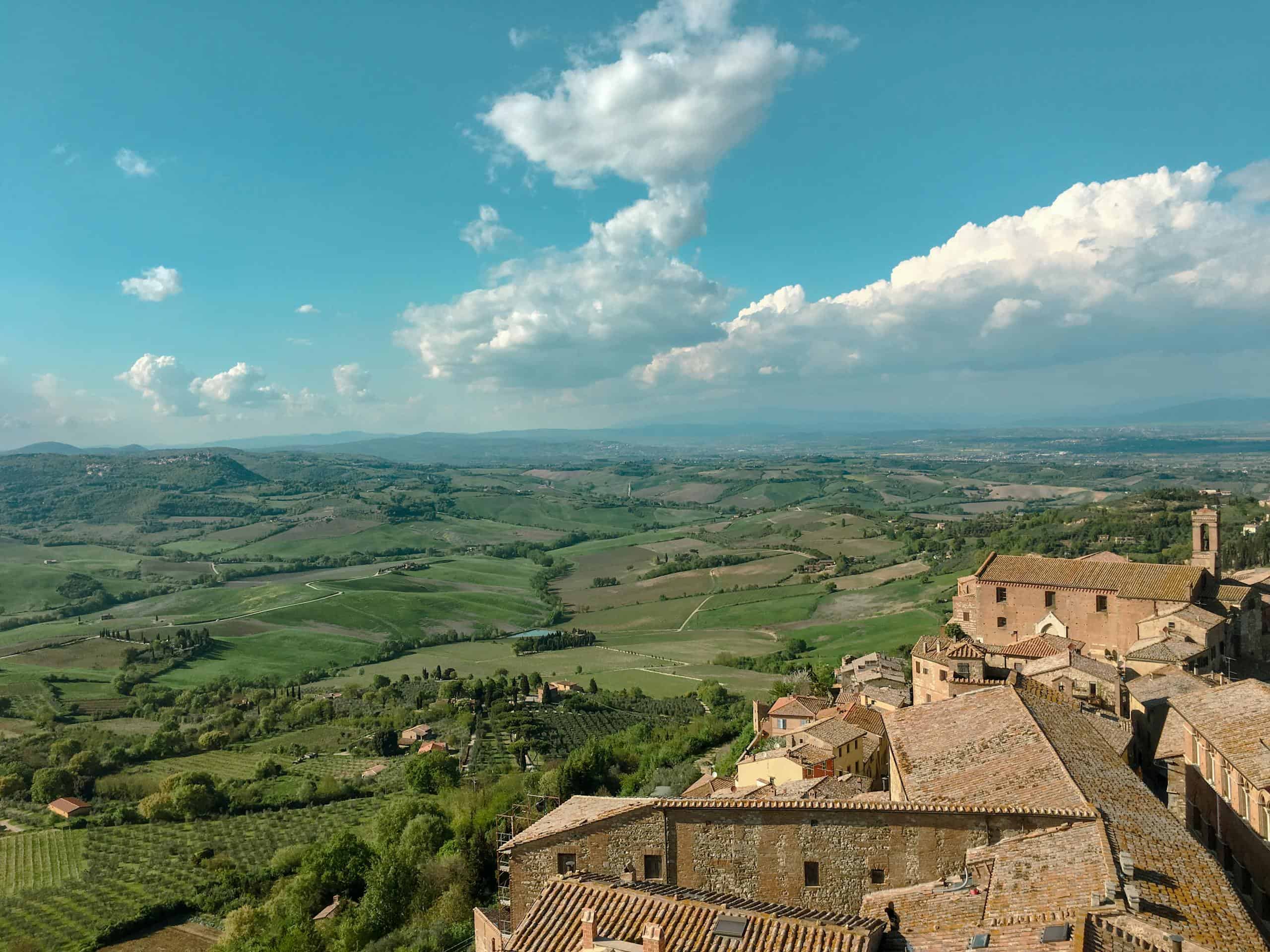 Beautiful panoramic view of a historic Italian village with lush landscape and blue sky.