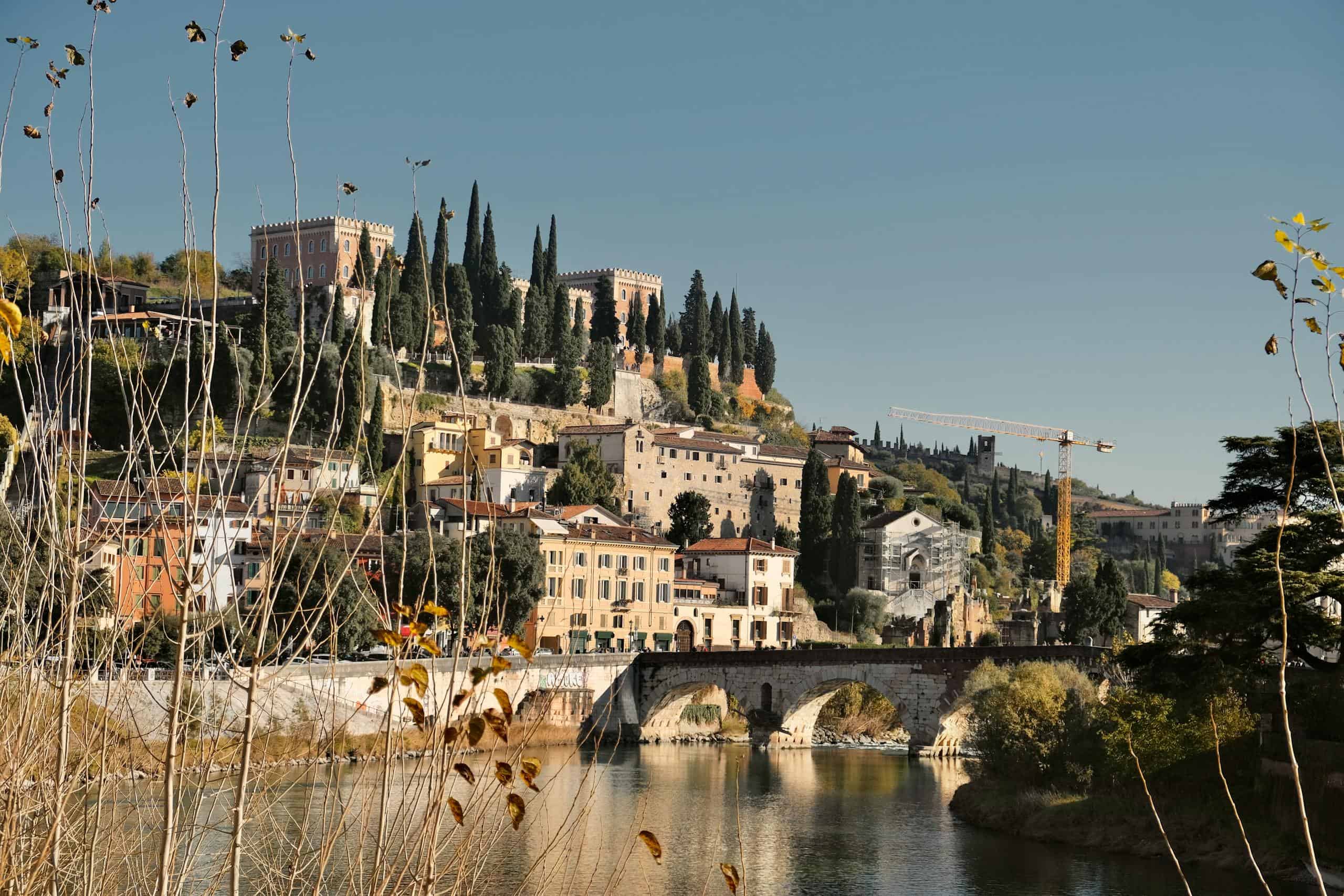 Scenic view of a historic European city with a river, bridge, and hillside buildings.