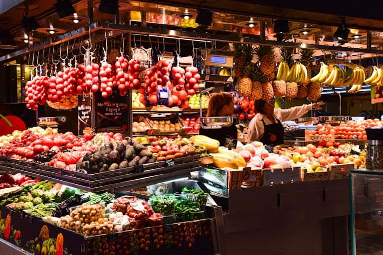 Vibrant fresh fruit market stall with a variety of colorful fruits including grapes, bananas, and me.