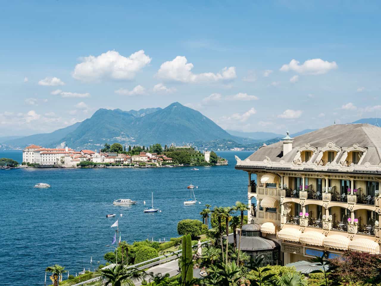 Scenic view of Lake Maggiore with mountains, boats, and lakeside hotel. Perfect for travel and vacat.