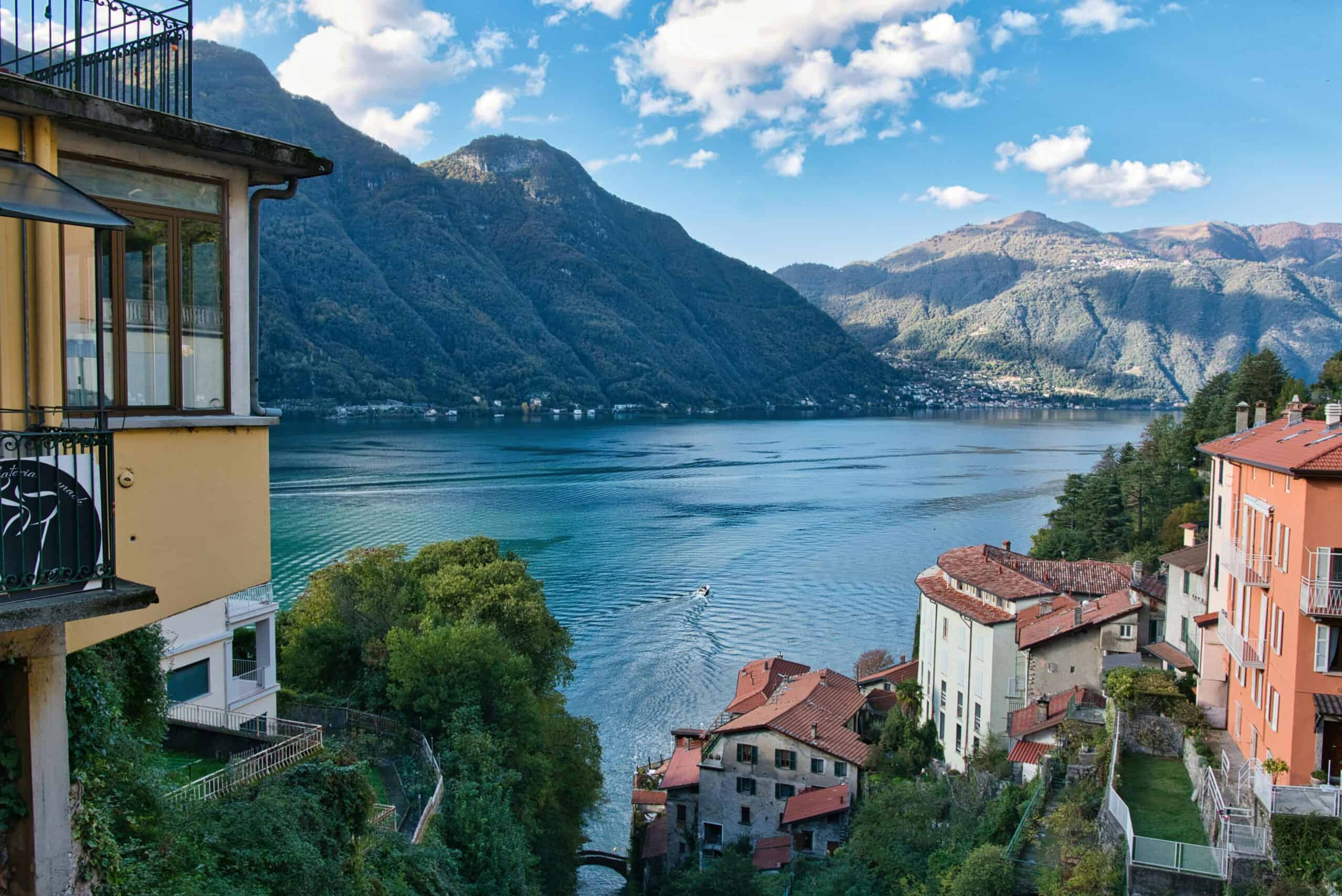 Beautiful Lake Como landscape featuring vibrant houses and lush green hills under a clear blue sky.