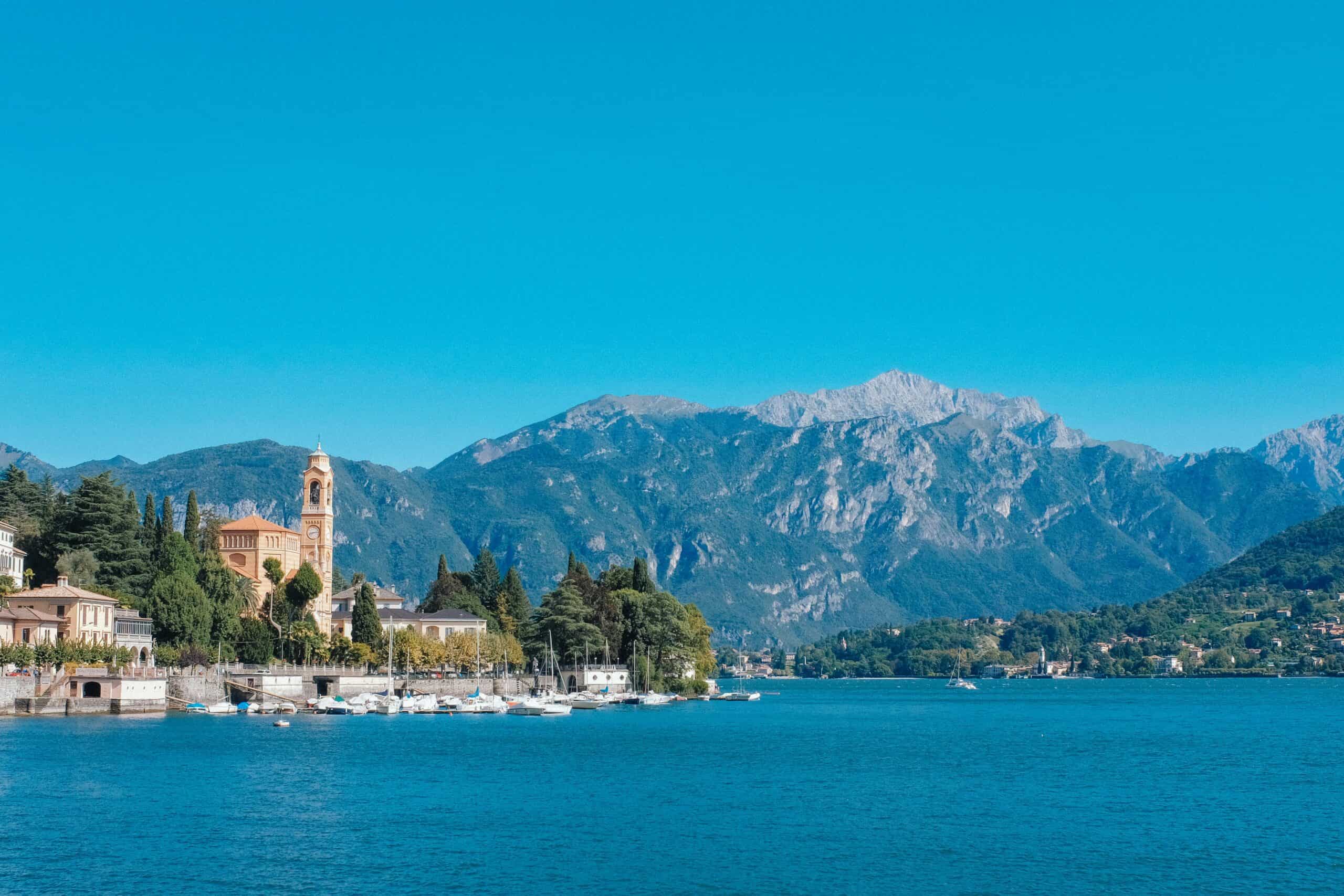 Scenic view of Lake Como with mountains, historic buildings, and boats on the water. Perfect for tra.