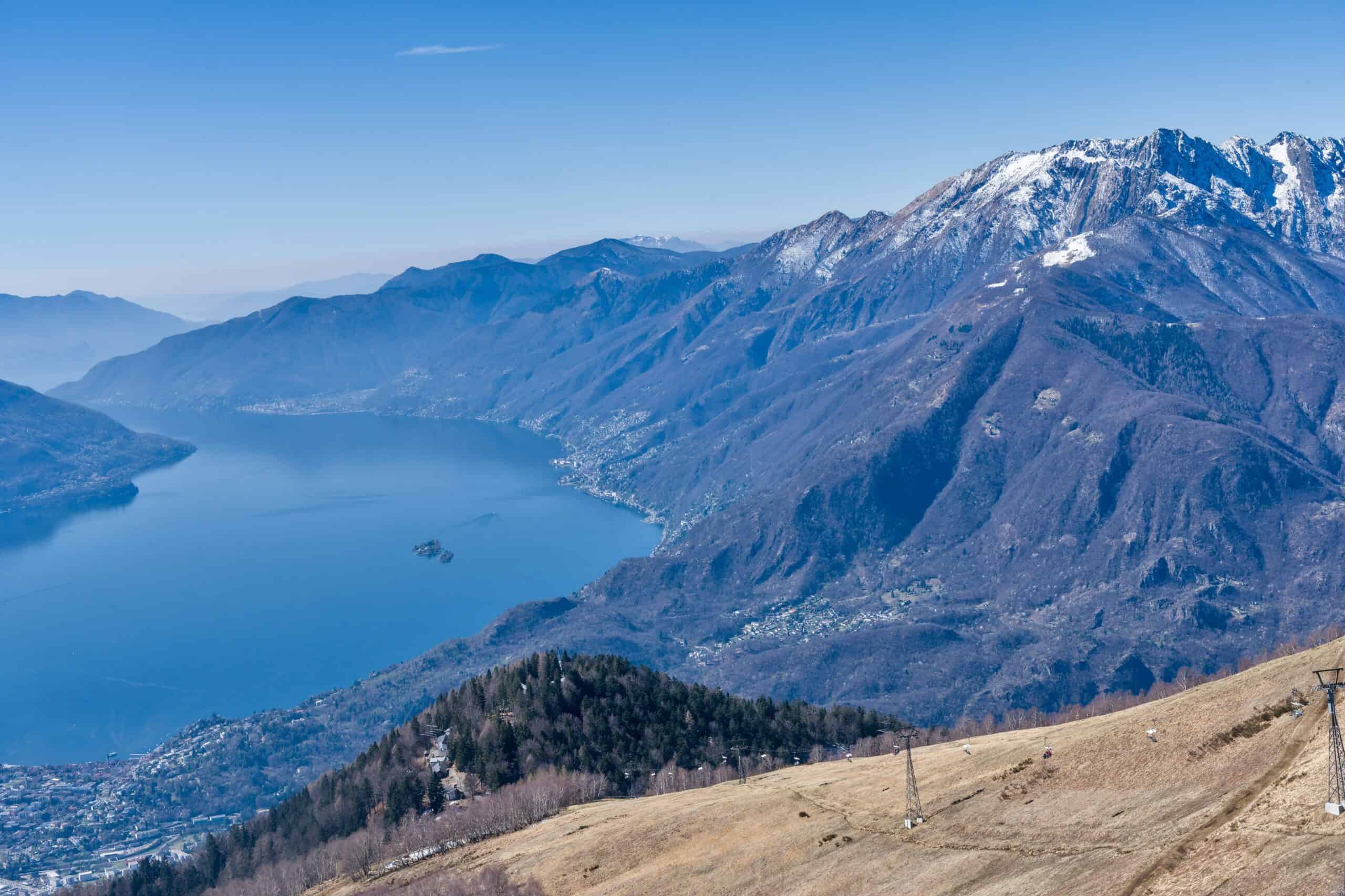 Mountain lake with snow-capped peaks and scenic hills in the background.
