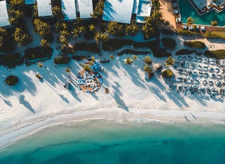 Beachfront resort in Riviera Maya with palm trees and clear turquoise waters.