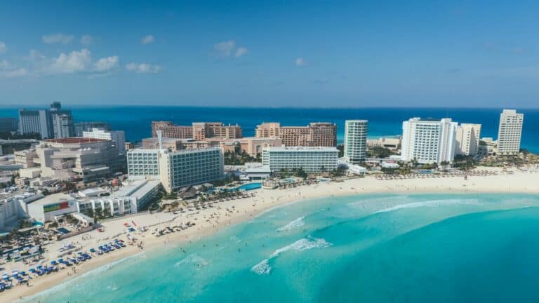 Beach cityscape with ocean view, sandy shoreline, and high-rise buildings.