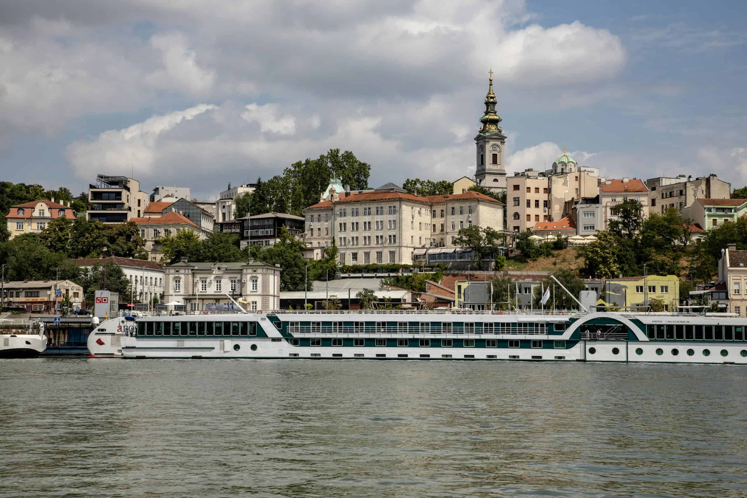 Historic European riverside cityscape with a cruise boat on the water.