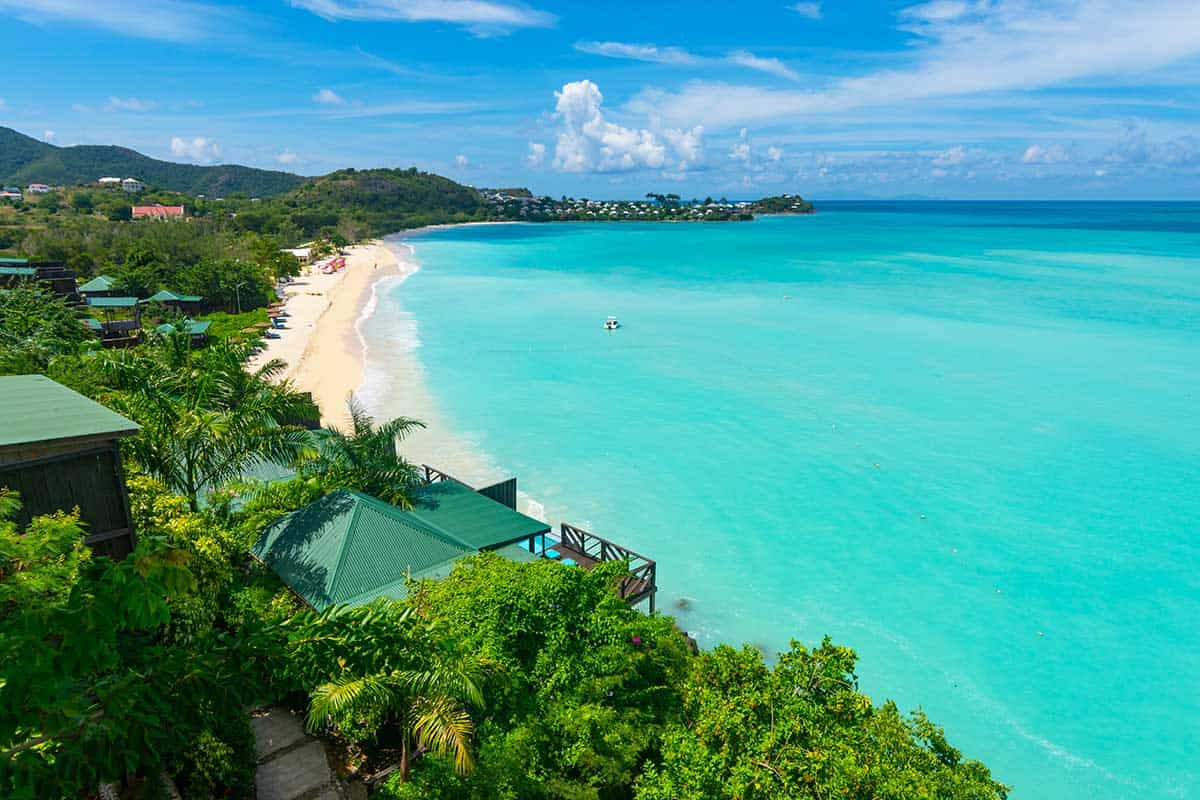 Tropical beach with turquoise waters, white sand, lush greenery, and scenic coastline, perfect for t.