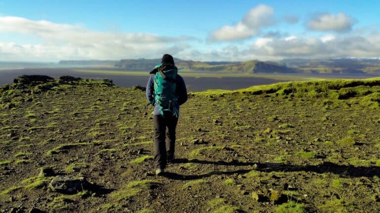 Hiker walking through moss-covered volcanic terrain in Iceland.