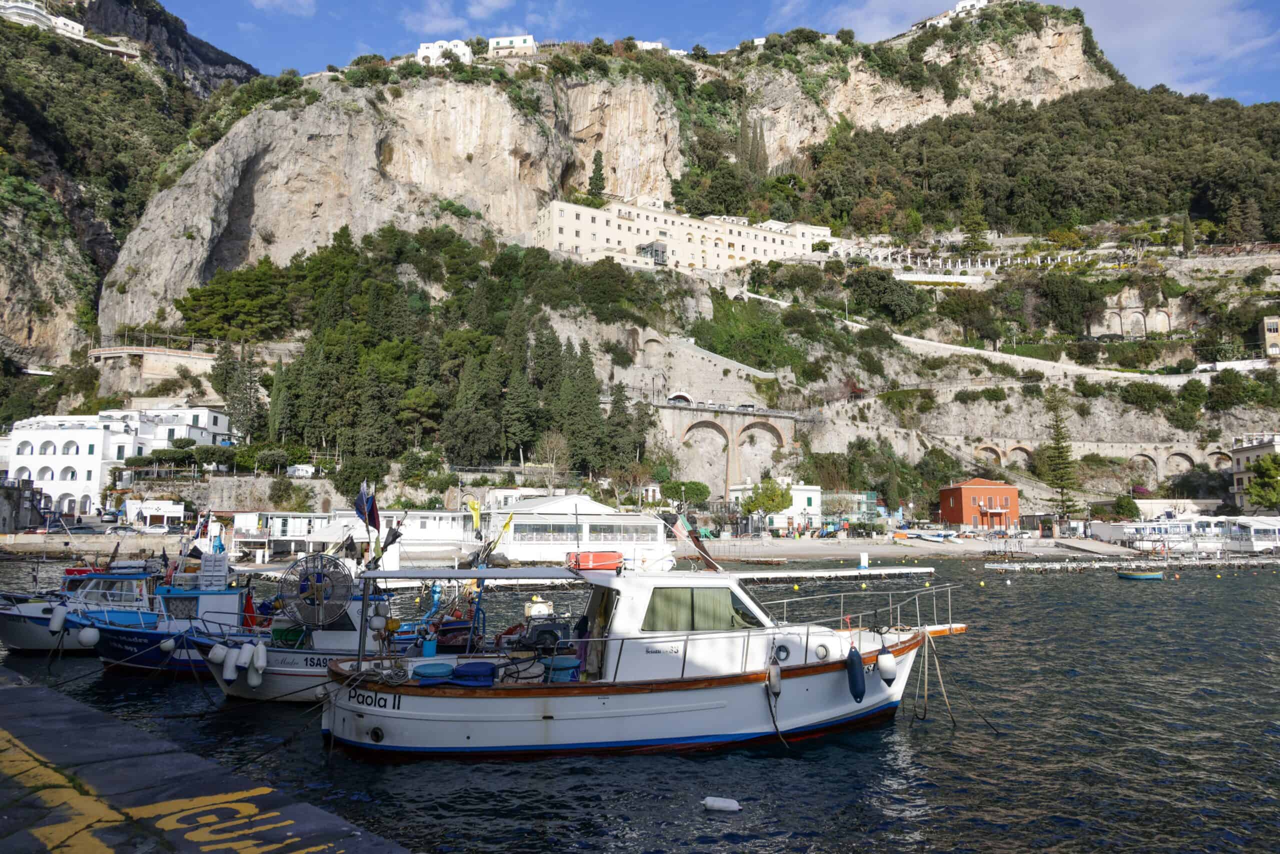 Scenic Amalfi Coast harbor with boats and towering cliffs in Italy.