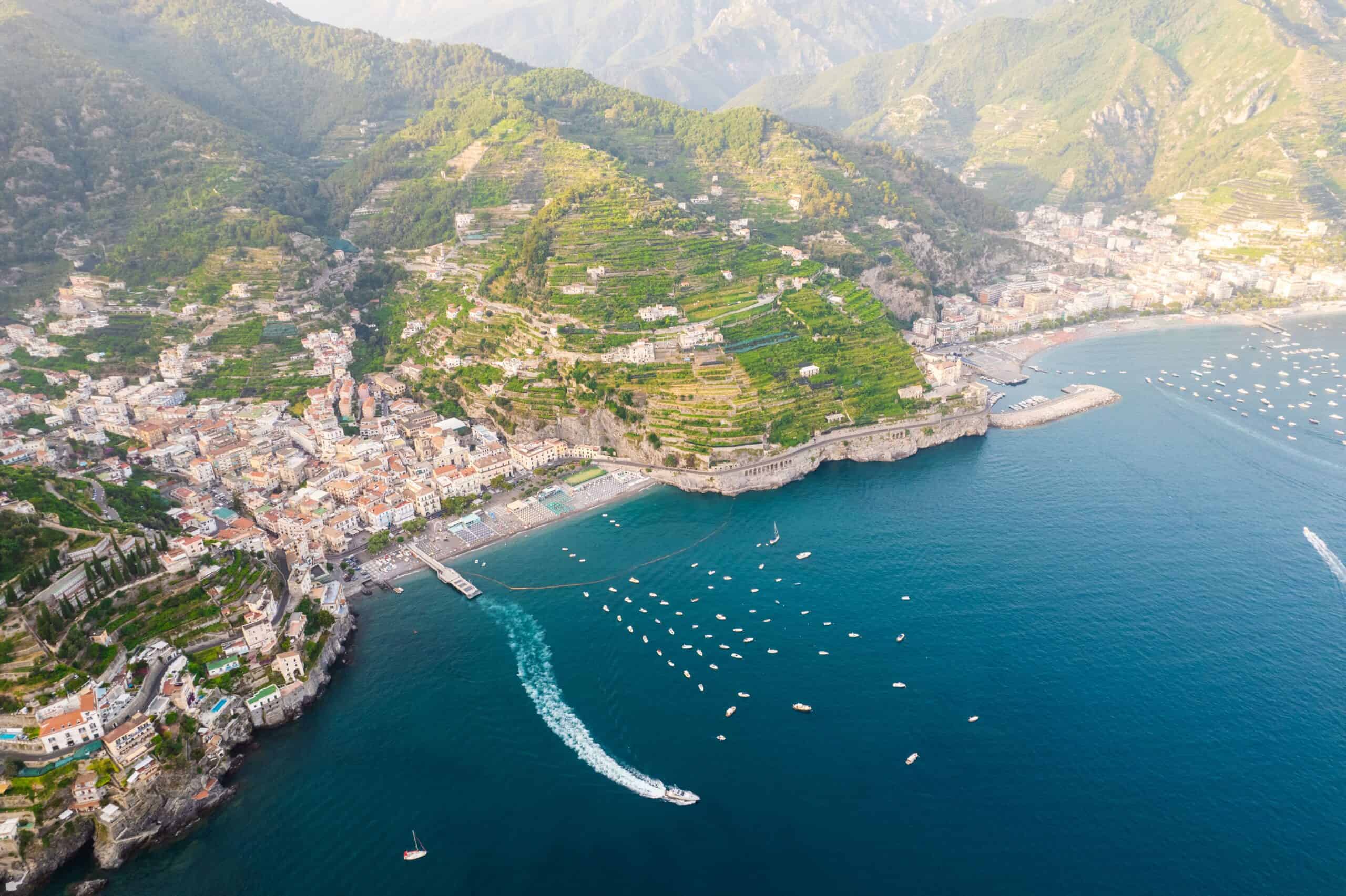 Aerial view of Amalfi Coast with boats and colorful coastal villages.