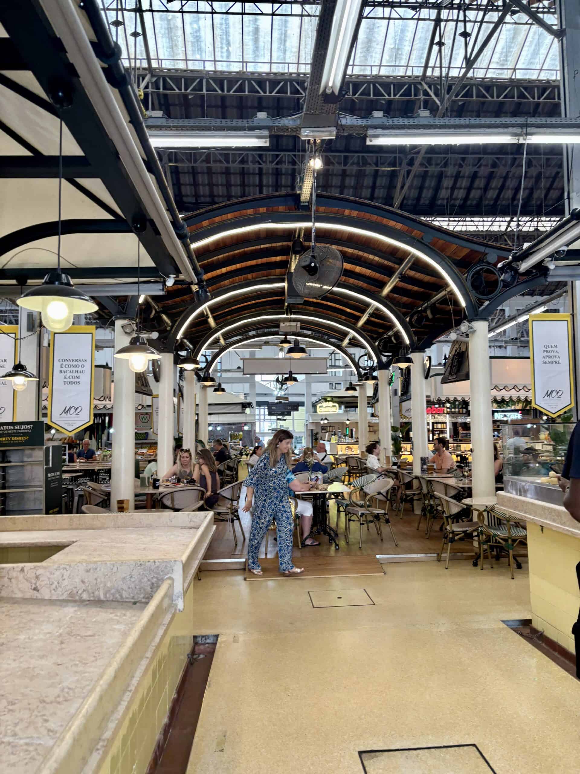 Indoor market with arched ceiling, vendors, and shoppers in Portugal.
