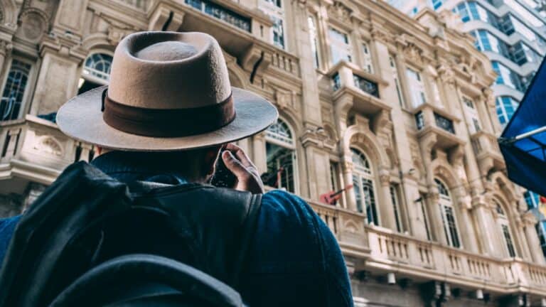 Traveling woman with hat exploring historic city architecture.